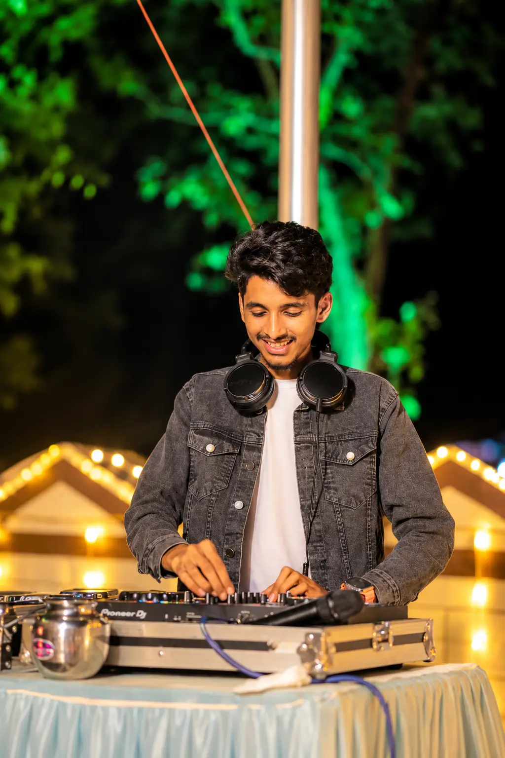 DJ Rev mixing at an outdoor night function under string lights
