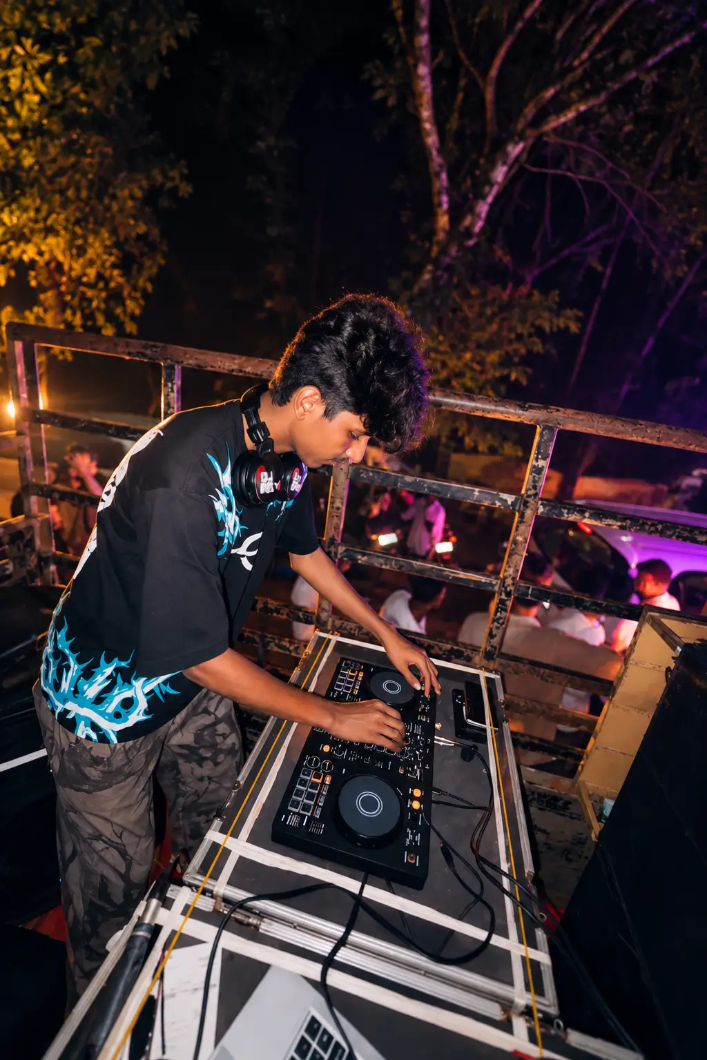 DJ Rev mixing on a raised open-air deck at night