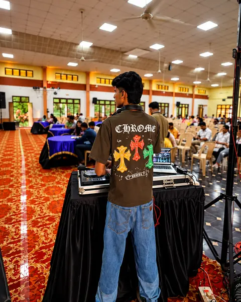 DJ Rev at his console facing a large reception hall with red carpet
